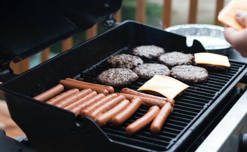 person standing in front grill grilling sausage